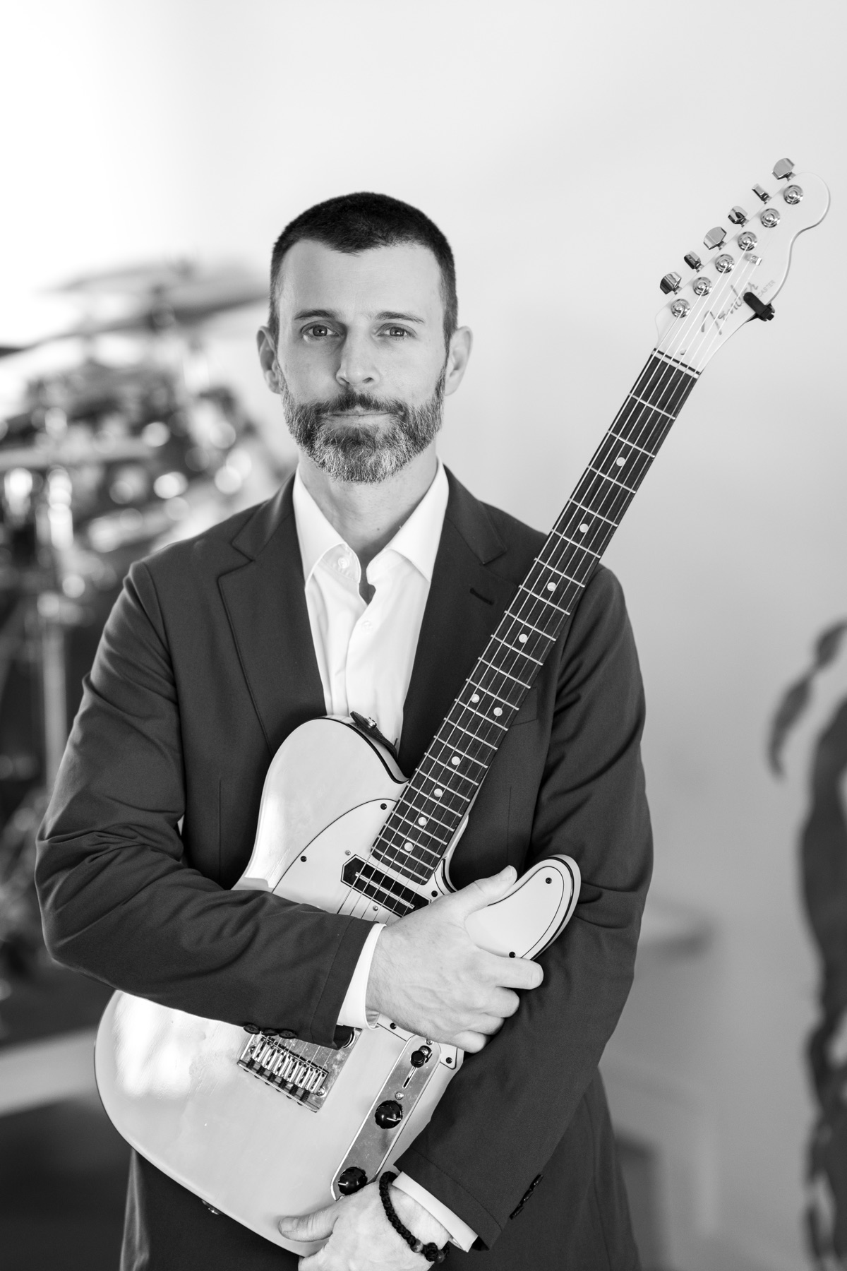 Coyah Gamble in a suit, holding his electric guitar across his chest